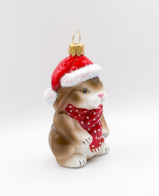 Kleiner braun-weisser Hase mit roter Mütze und Schal