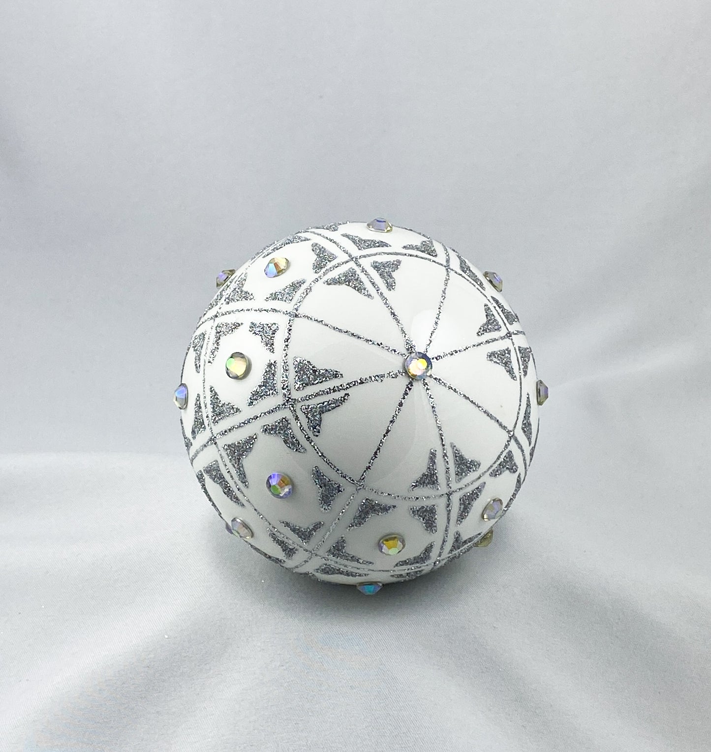 Kugel weiss mit geometrischem Muster und irisierenden Schmucksteinen