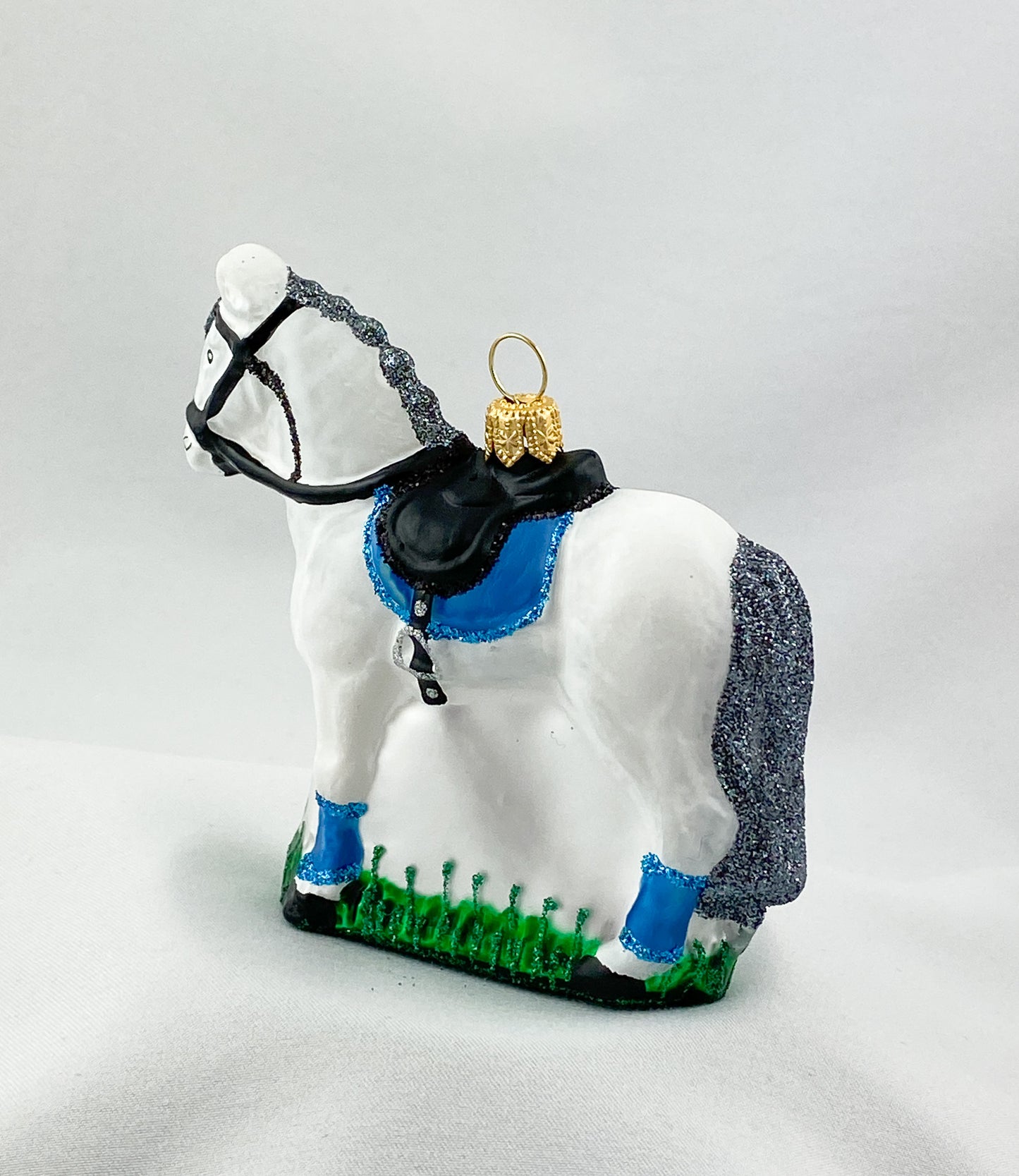 Weisses Pferd mit blauer Satteldecke