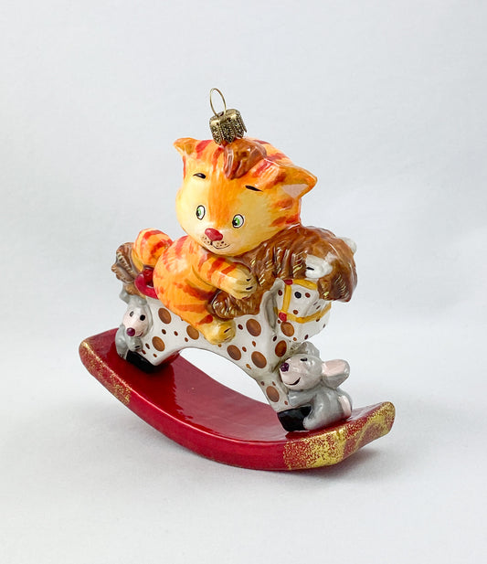 The red tiger cat rides on the spotted rocking horse AtlasArt
