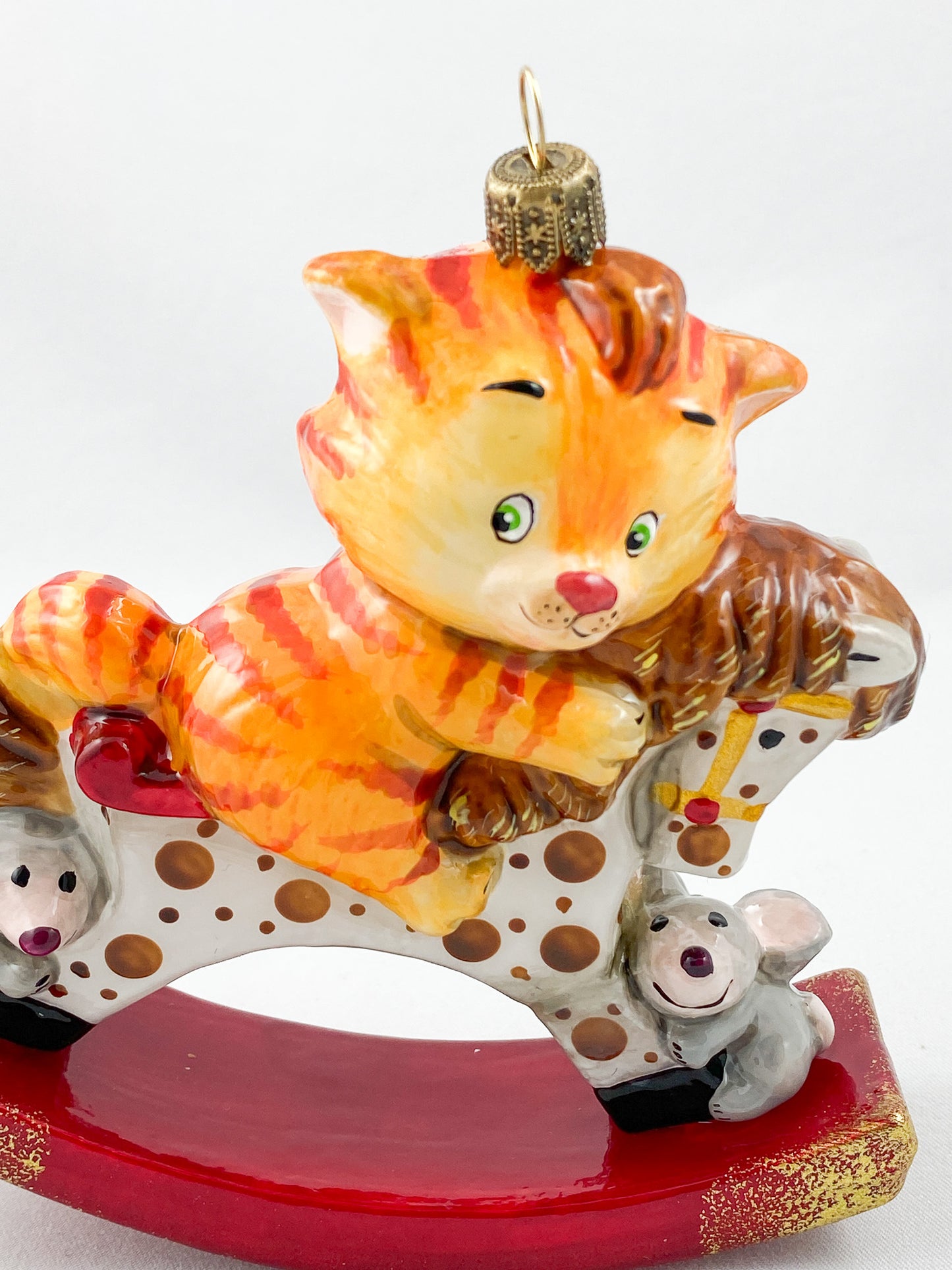The red tiger cat rides on the spotted rocking horse AtlasArt