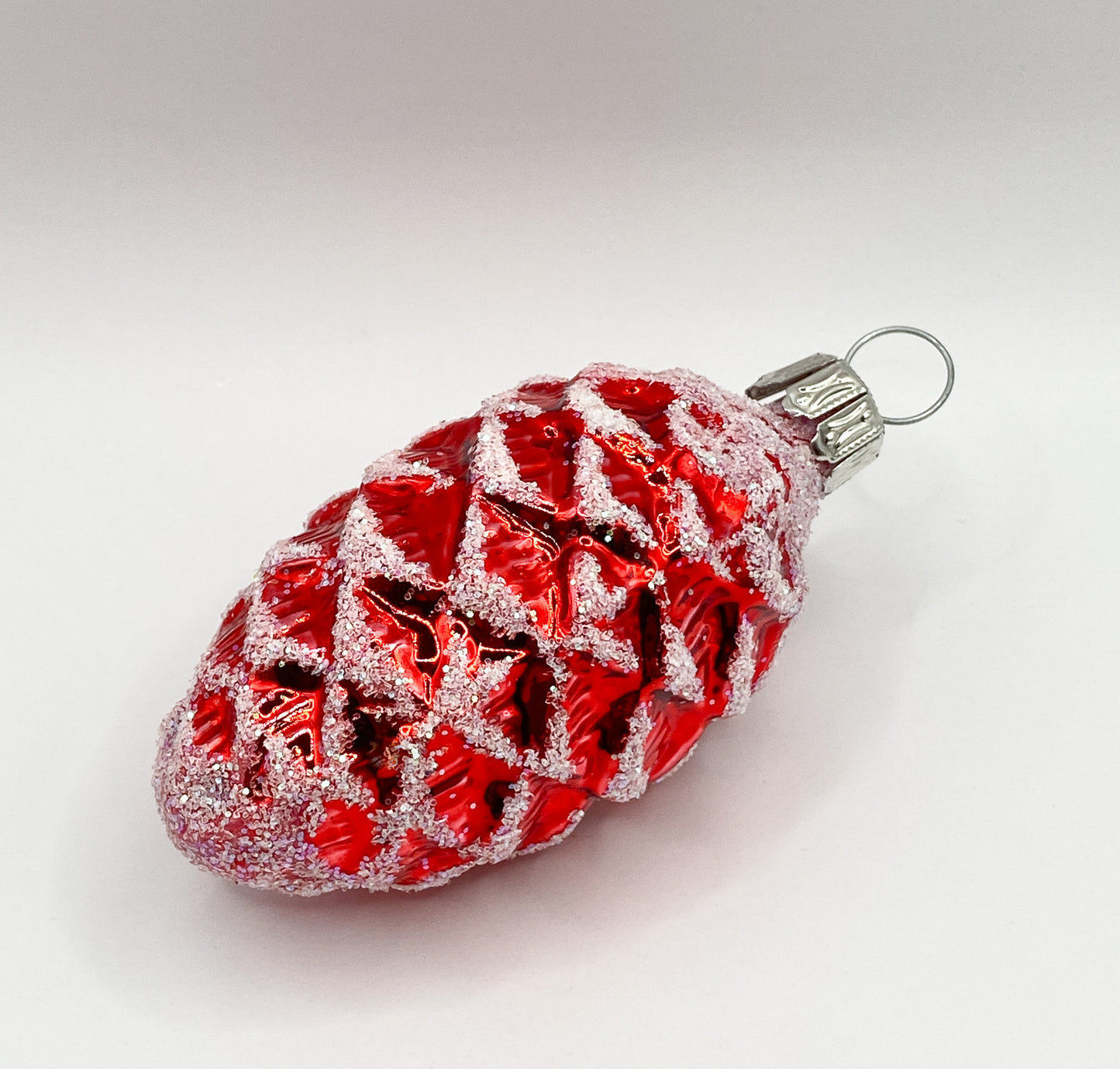 Small red shiny fir cone with white glitter