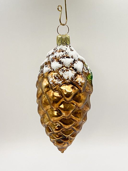 Snowy brown pine cone with goldfinch