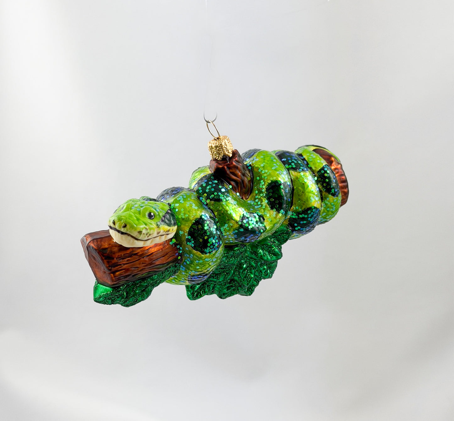 Green anaconda slithers around tree trunk