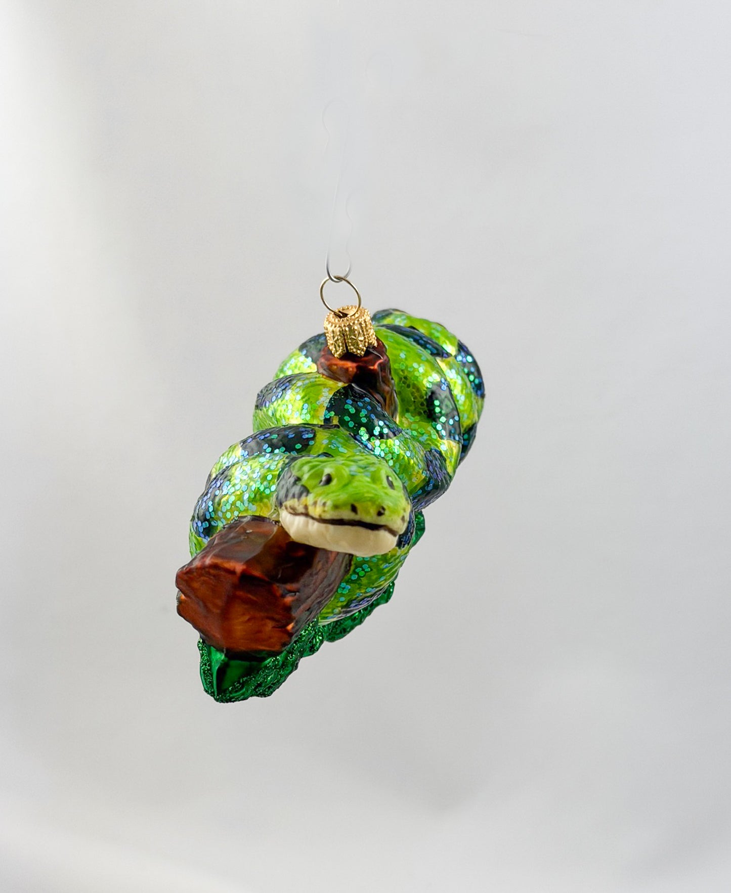 Green anaconda slithers around tree trunk