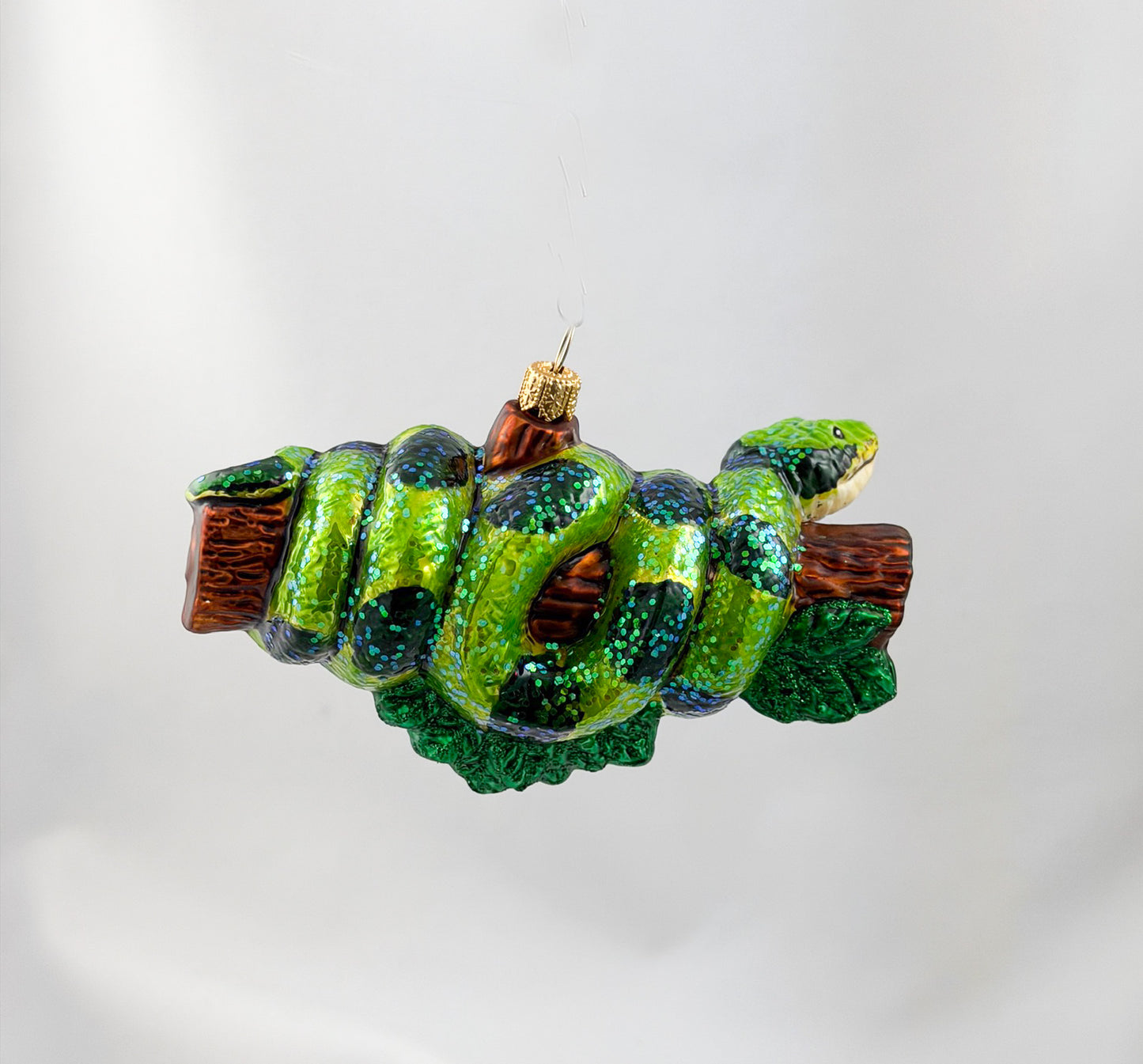 Green anaconda slithers around tree trunk