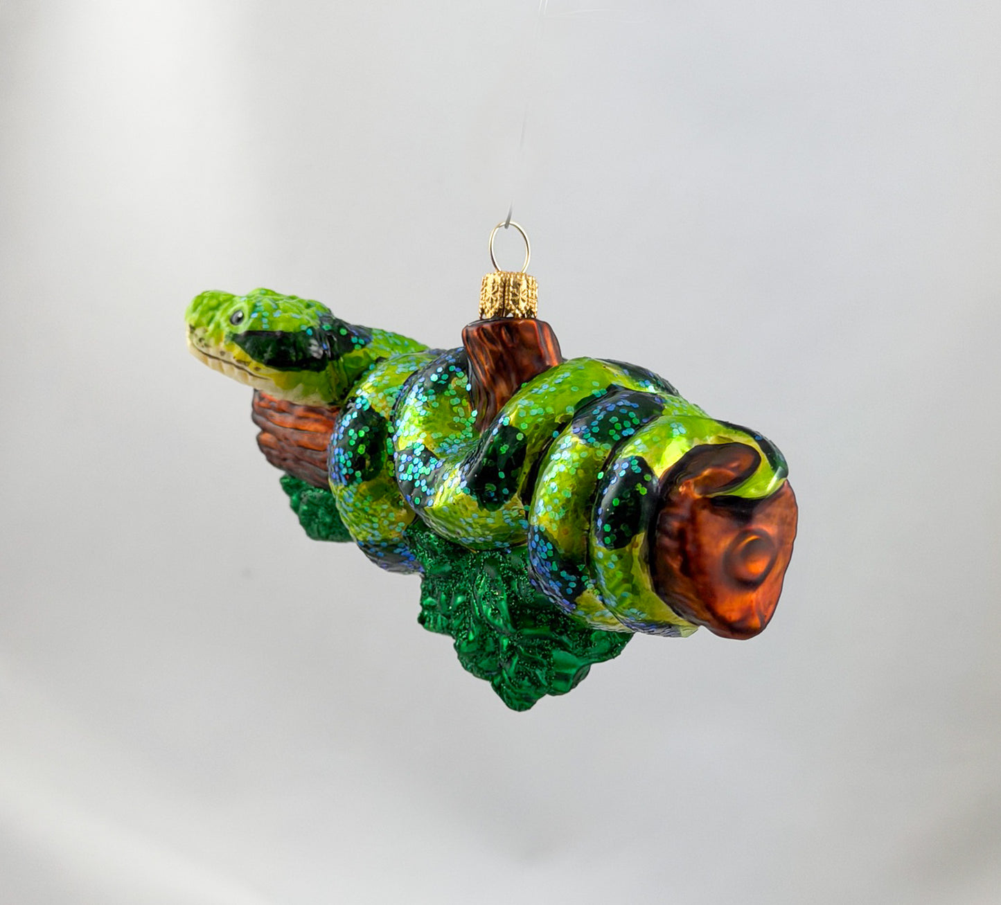 Green anaconda slithers around tree trunk
