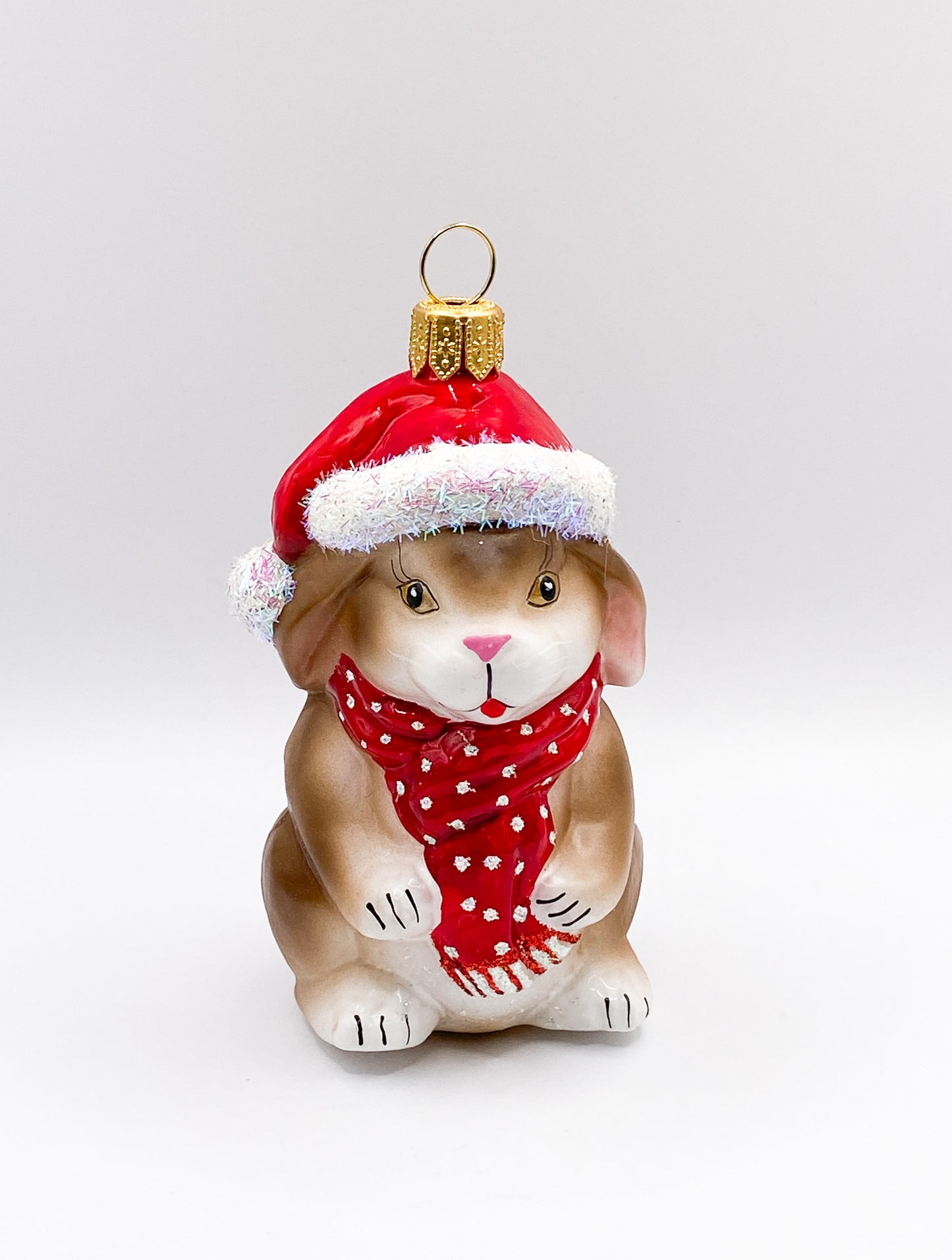Kleiner braun-weisser Hase mit roter Mütze und Schal
