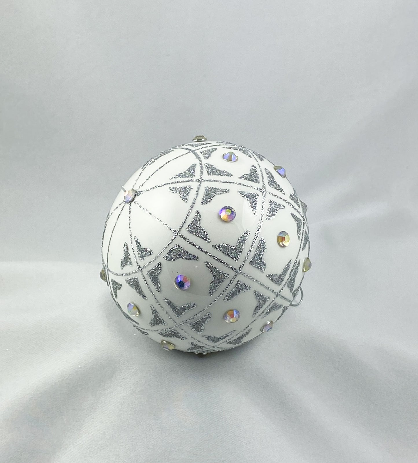 Kugel weiss mit geometrischem Muster und irisierenden Schmucksteinen