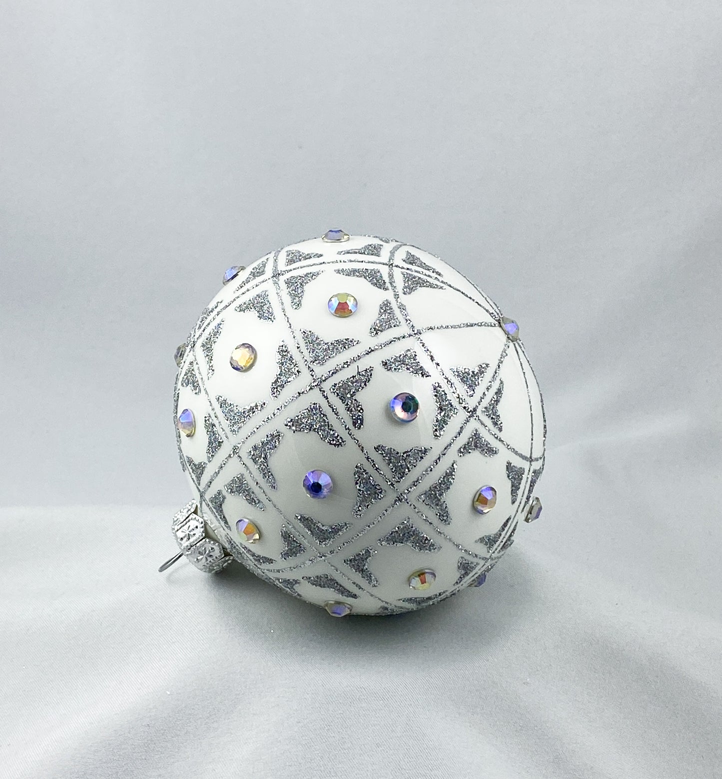 Kugel weiss mit geometrischem Muster und irisierenden Schmucksteinen