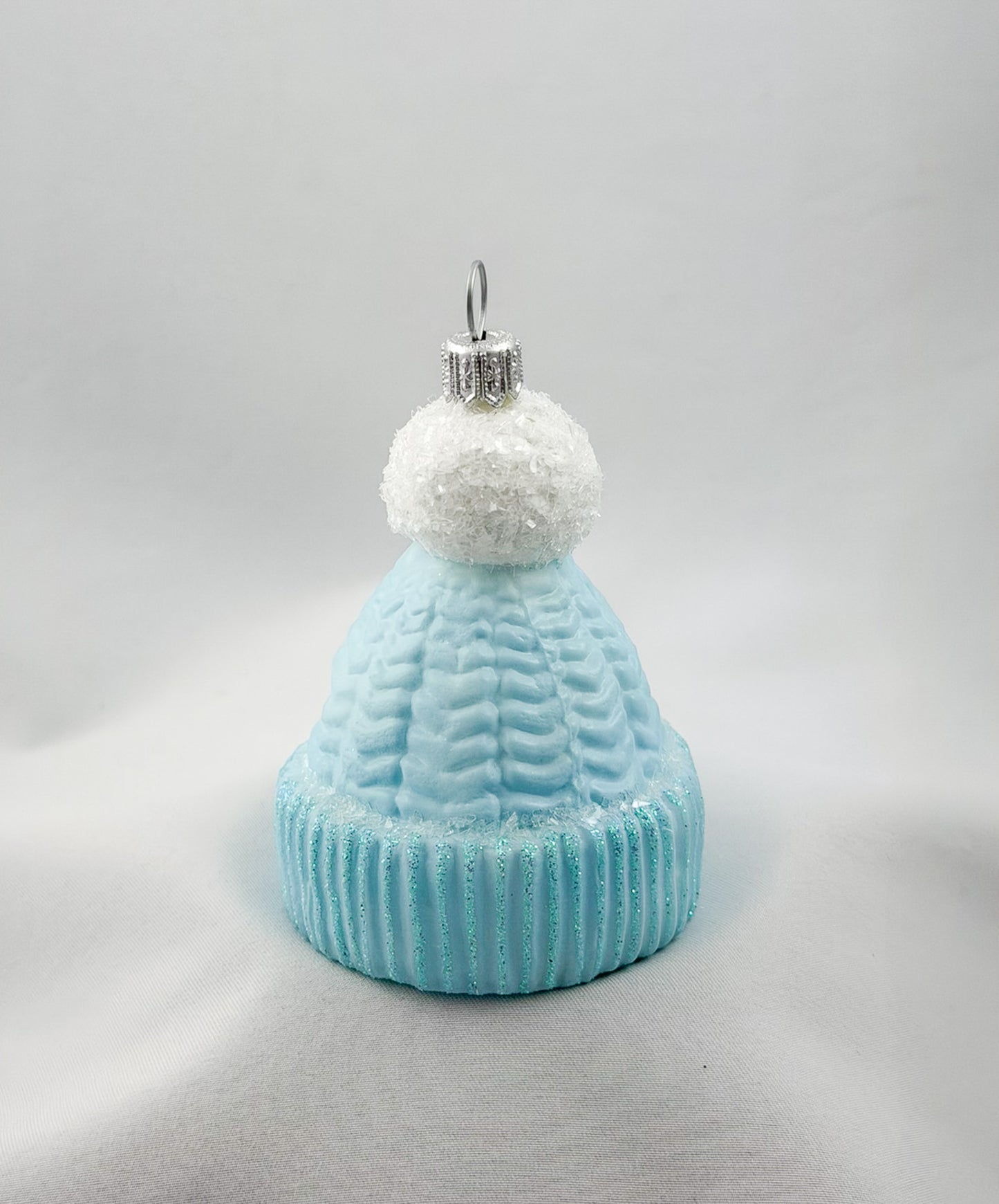 Light blue knitted hat with white pom-pom