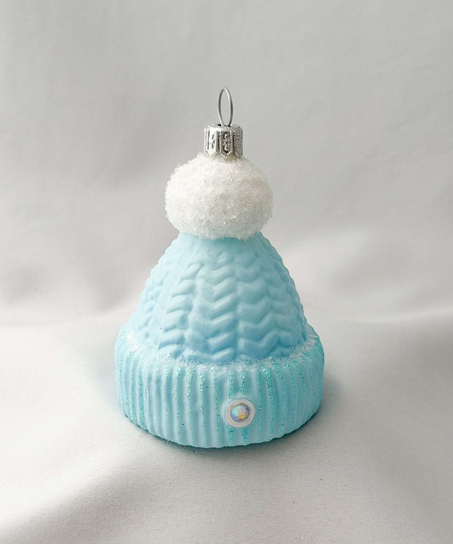 Light blue knitted hat with white pom-pom