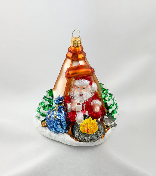 Santa is sitting comfortably in his tent by the campfire.
