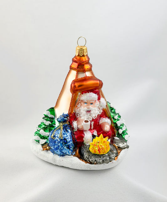 Santa is sitting comfortably in his tent by the campfire.