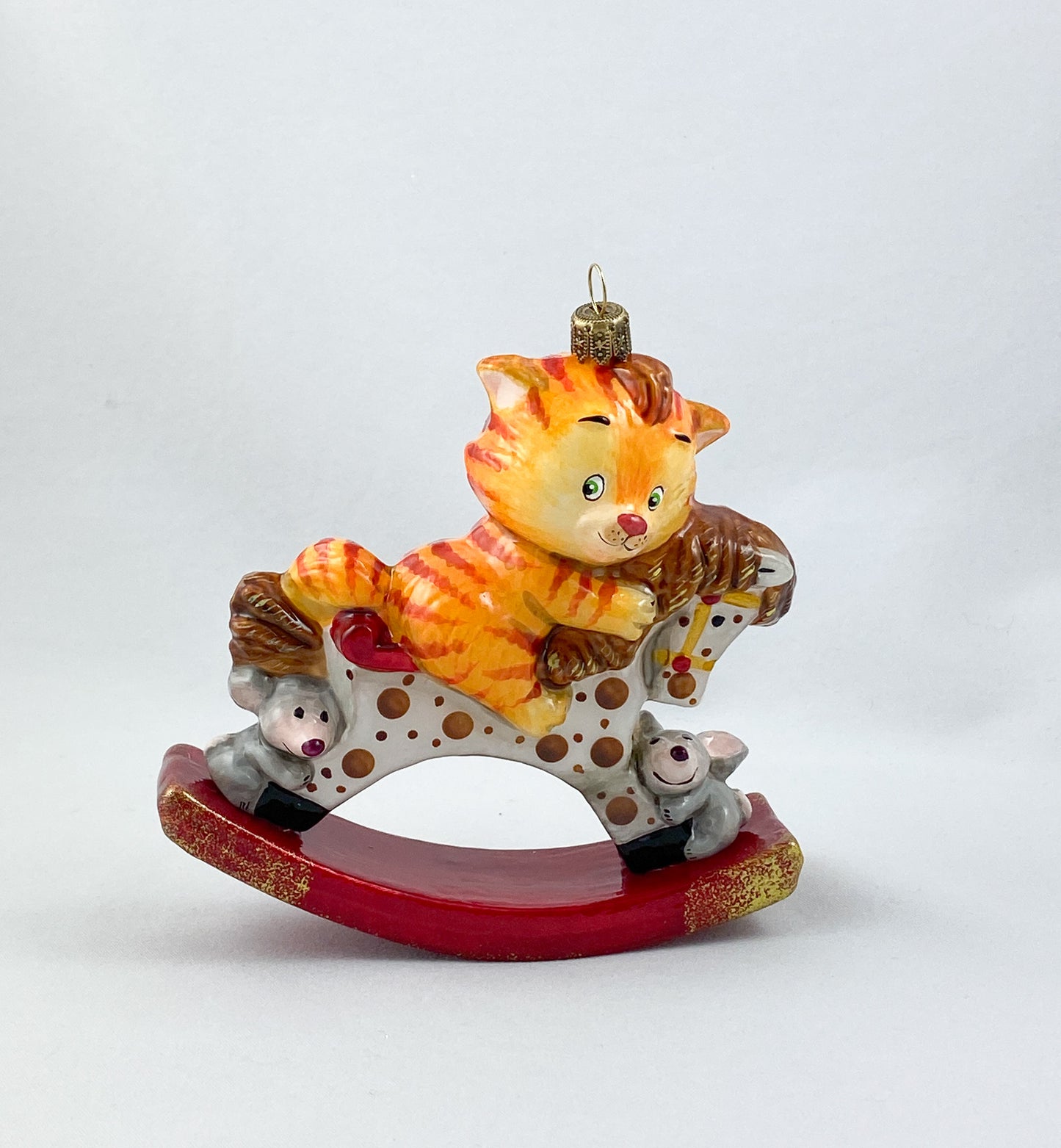 The red tiger cat rides on the spotted rocking horse AtlasArt