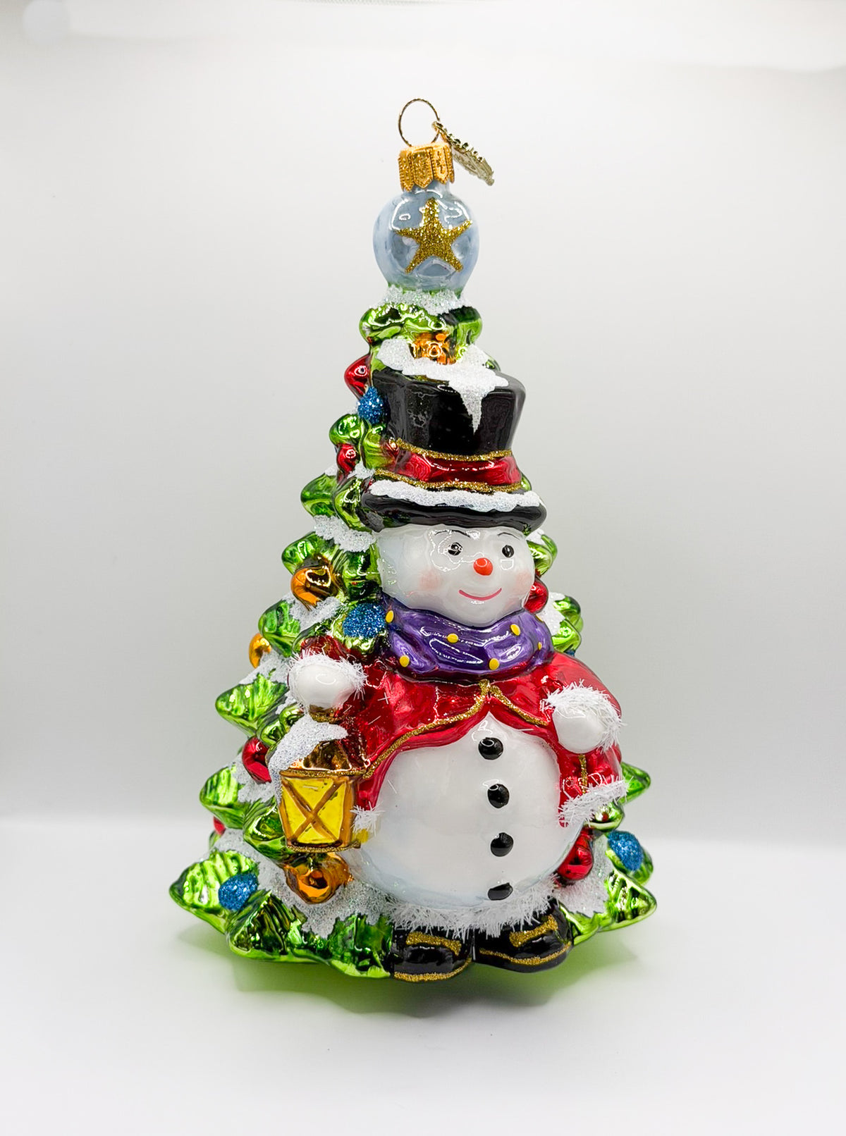 Schneemann mit Laterne steht vor dem Weihnachtsbaum