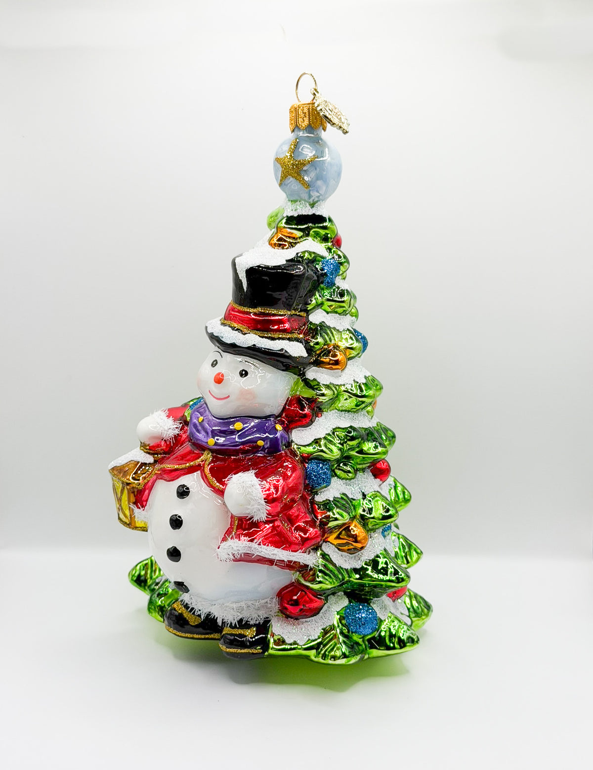 Schneemann mit Laterne steht vor dem Weihnachtsbaum