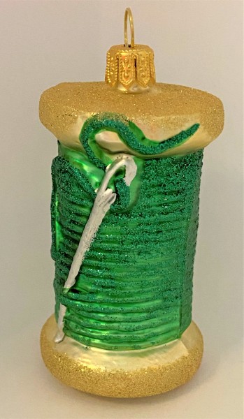 Grüne Fadenspule mit Nähnadel
