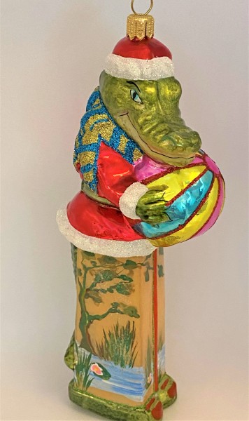 Krokodil im Santa-Kostüm spielt mit dem Ball