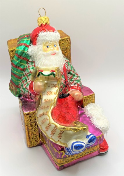 Santa Claus sitzt bequem im Sessel und studiert die Geschenke-Liste